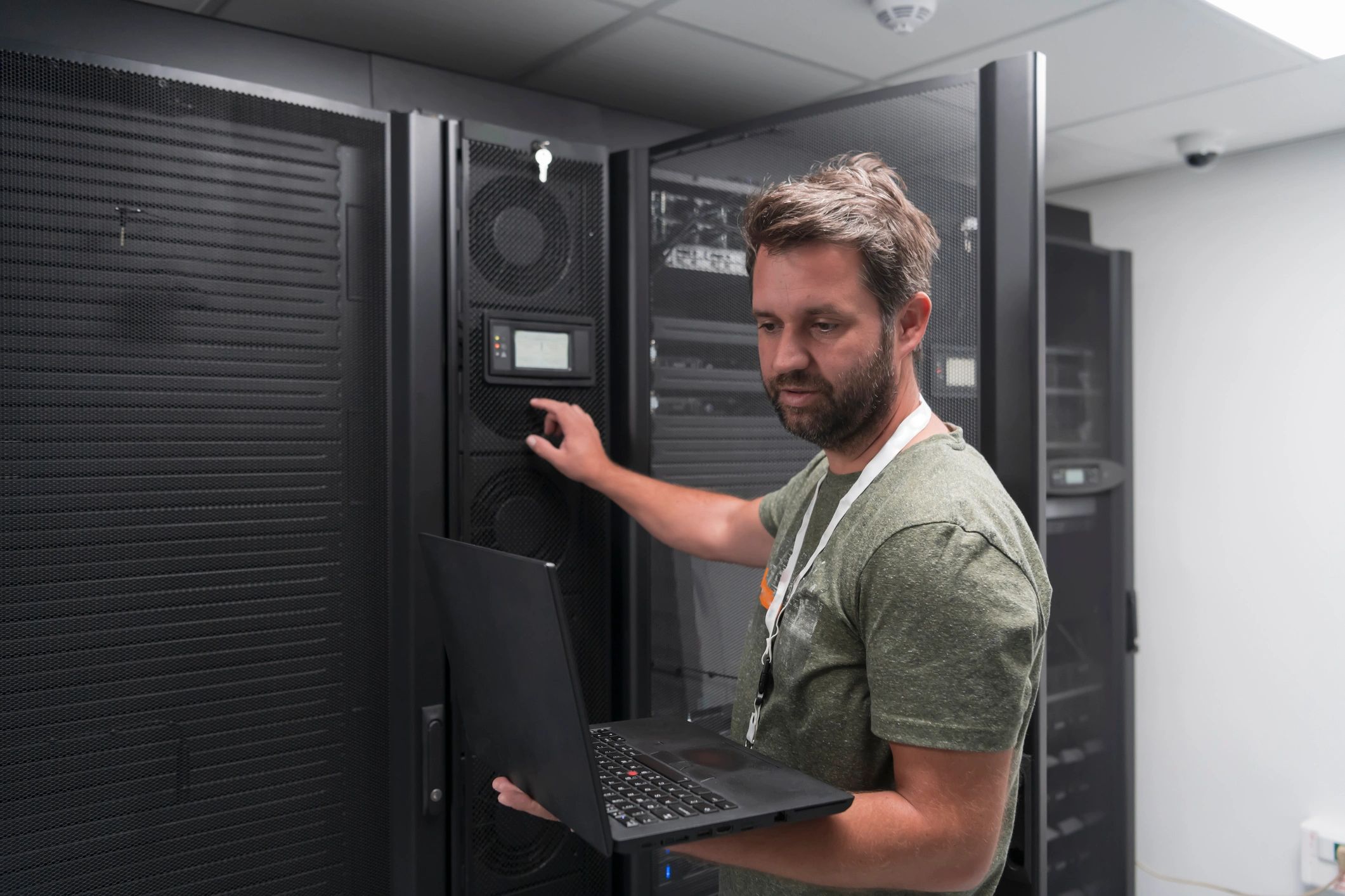 IT technician using a laptop in a server room