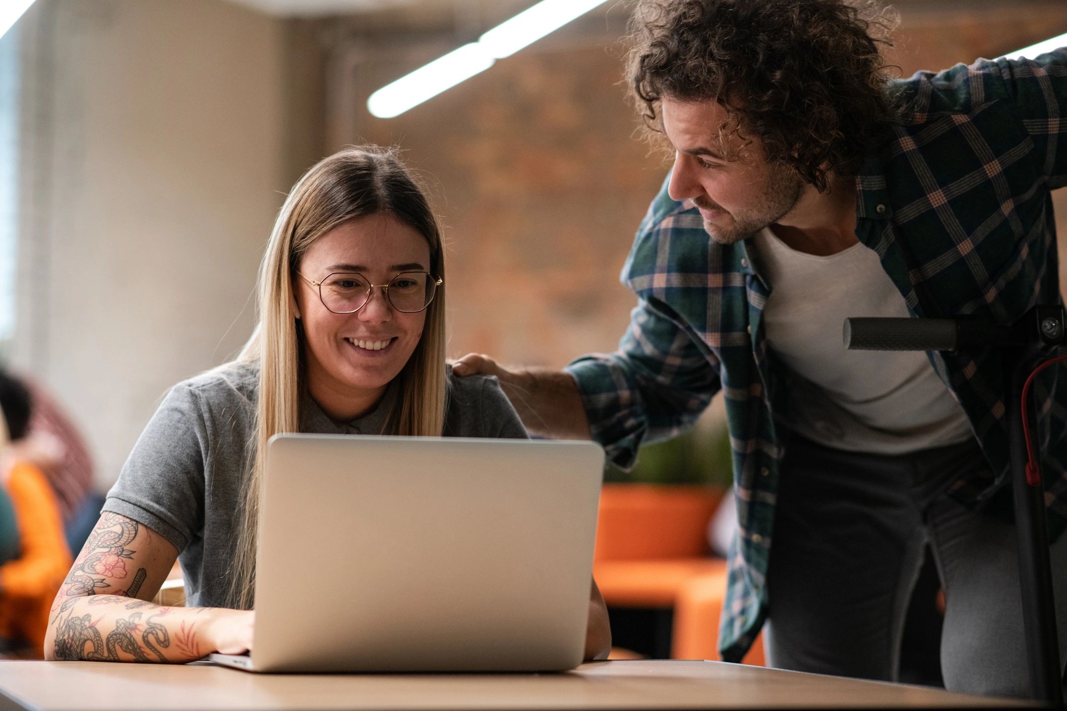 Two coworkers discussing a laptop during IT support